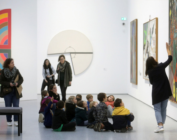 Médiatrice culturelle s'exprimant devant des visiteurs, dans une exposition