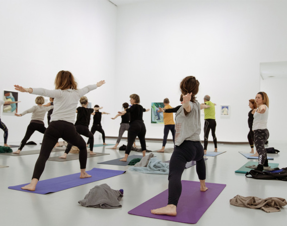 Visiteurs faisant du yoga dans une salle d'exposition du musée