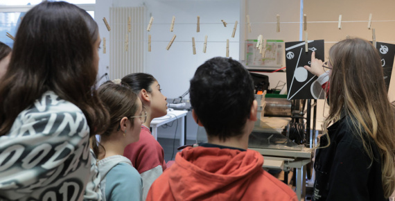 Dans un atelier, une médiatrice montre une image à des adolescents.