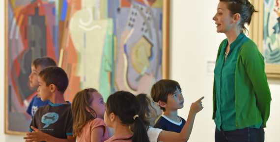 Médiatrice culturelle s'exprimant devant des jeunes visiteurs dans une exposition