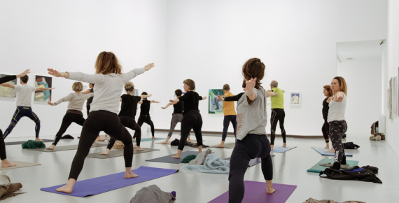 Visiteurs faisant du yoga dans une salle d'exposition du musée