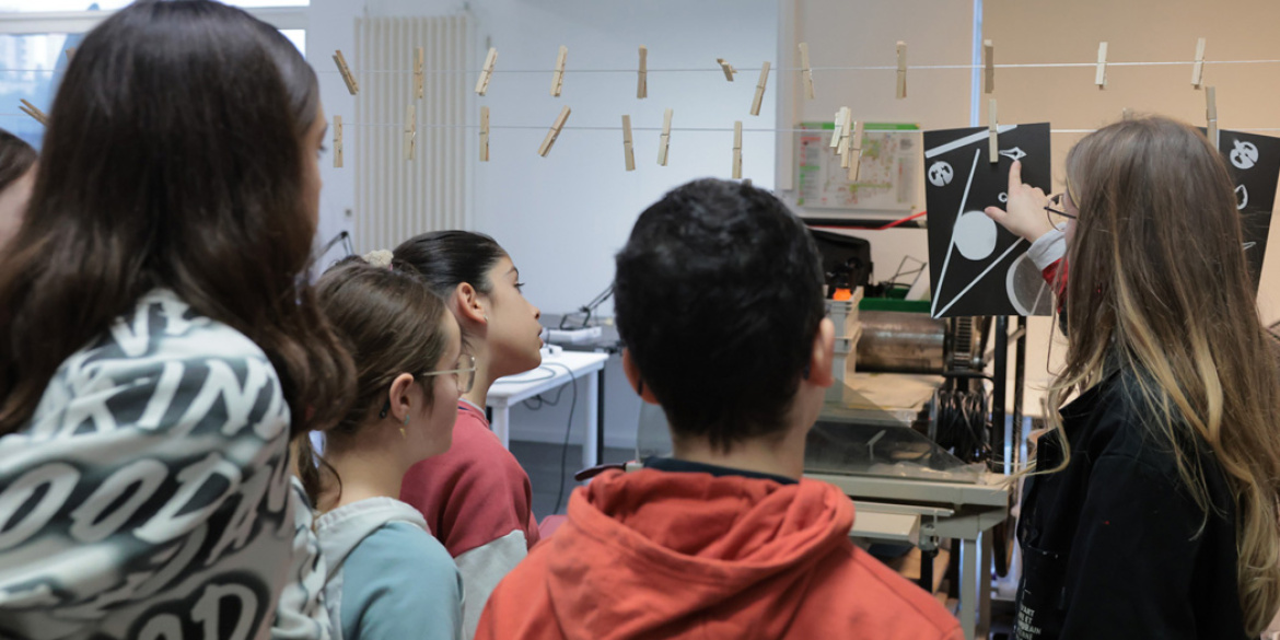 Dans un atelier, une médiatrice montre à des adolescents une image.