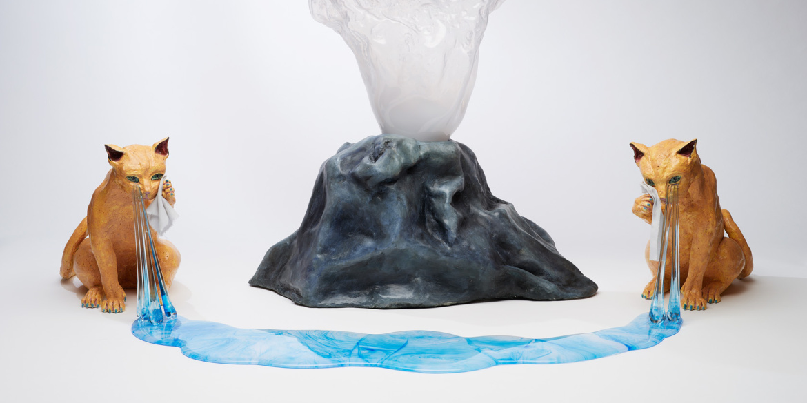 Sculptures en verre de deux animaux pleurant autour d'un volcan, formant une rivière autour de celui-ci.